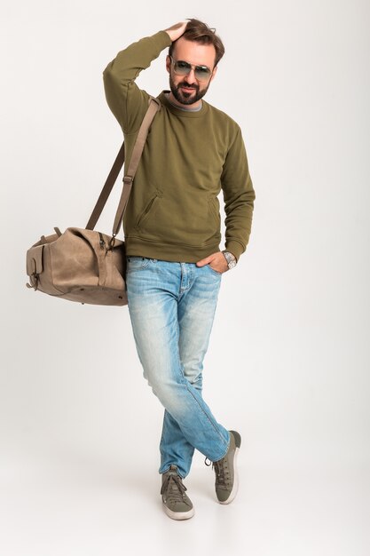 Viaggiatore attraente uomo alla moda isolato in piedi con borsa bello vestito in jeans e sudore