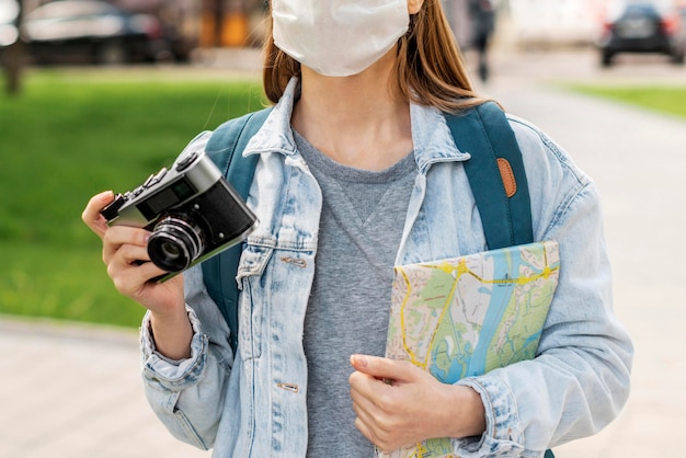 Viaggiatore che indossa la mappa medica e la macchina fotografica della tenuta della maschera