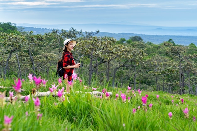 Viaggiatore della donna con lo zaino che gode al campo dei fiori di Krachiew, Tailandia. Concetto di viaggio.