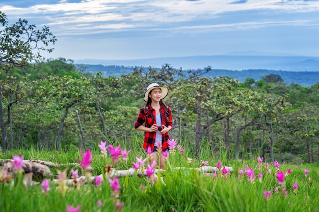 Viaggiatore della donna con lo zaino che gode al campo dei fiori di Krachiew, Tailandia. Concetto di viaggio.