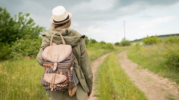 Viaggiatore di vista posteriore con il cappello che cammina all'aperto