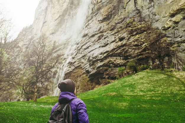 Viaggiatore donna in piedi e guardando una bellissima cascata di montagna