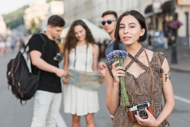 Viaggiatore femminile con fiori e macchina fotografica