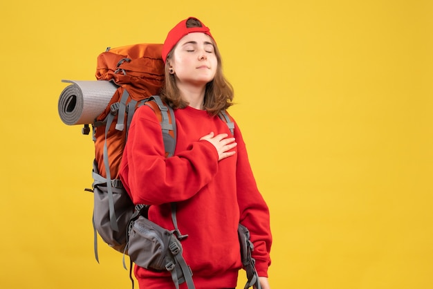 Viaggiatore femminile freddo vista frontale con zaino chiudendo gli occhi mettendo la mano sul petto