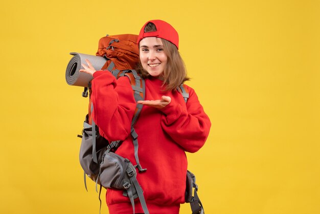 Viaggiatore femminile sorridente di vista frontale con lo zaino che indica allo zaino