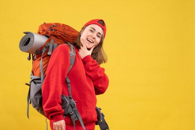 Viaggiatore femminile sorridente di vista frontale con lo zaino che mette la mano sul suo mento