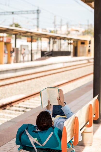 Viaggiatore leggendo un libro e aspettando il treno