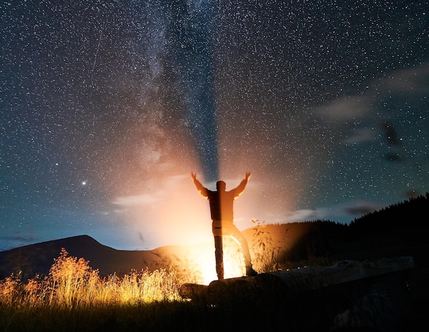 Viaggiatore maschio in piedi sotto il bellissimo cielo notturno con le stelle