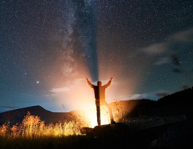 Viaggiatore maschio in piedi sotto il bellissimo cielo notturno con le stelle