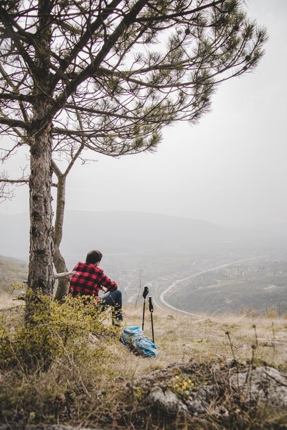 Viaggiatore seduto accanto a un albero