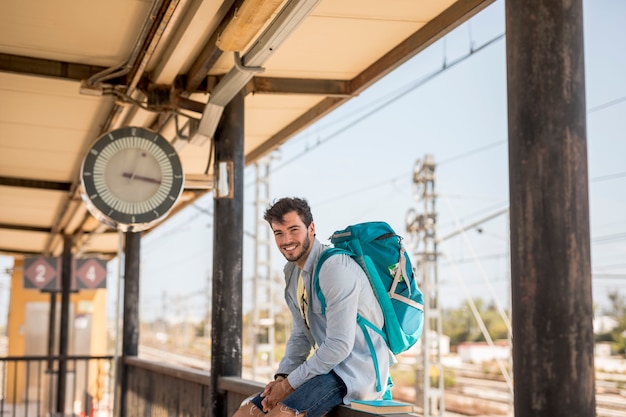 Viaggiatore sorridente che aspetta il treno