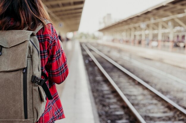 Viaggiatore zaino in spalla di giovane donna asiatica che cammina da solo alla piattaforma della stazione ferroviaria con lo zaino