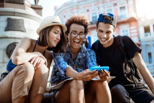 Viaggiatori di amici con zaini sorridenti, selfie, seduti vicino alla vista.