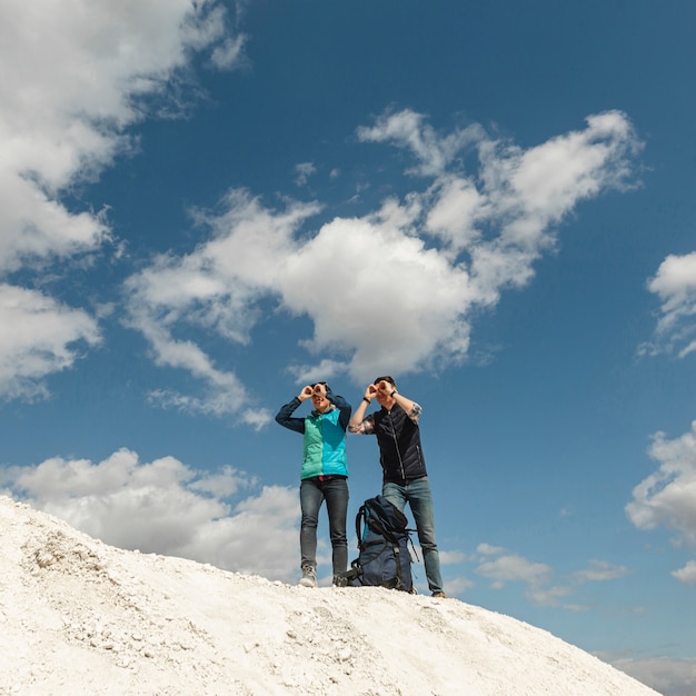 Viaggiatori long shot con binocolo