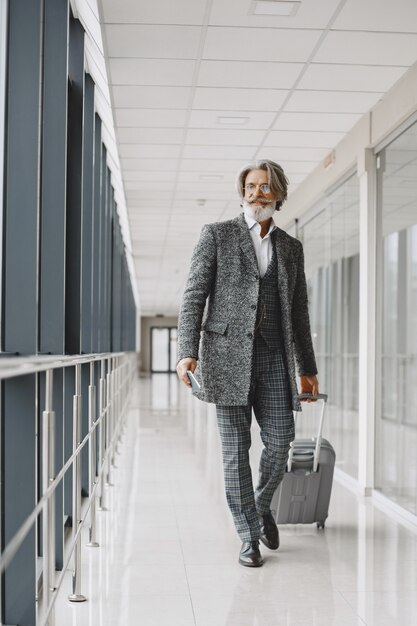 Viaggio di lavoro. Concetto aziendale e di persone. Maschio con mantello grigio. Senior con un passaporto.