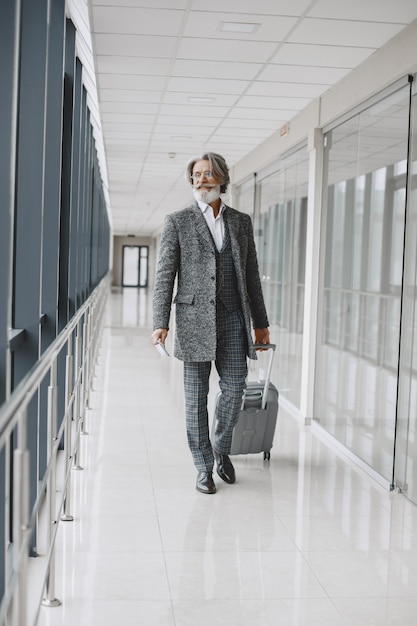 Viaggio di lavoro. Concetto aziendale e di persone. Maschio con mantello grigio. Senior con un passaporto.