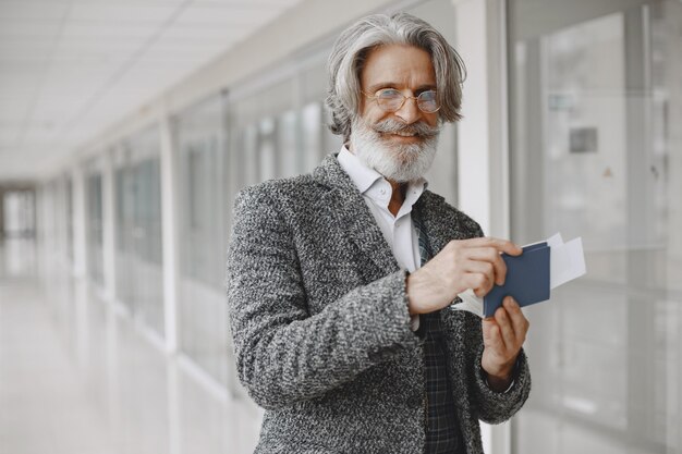 Viaggio di lavoro. Concetto aziendale e di persone. Maschio con mantello grigio. Senior con un passaporto.