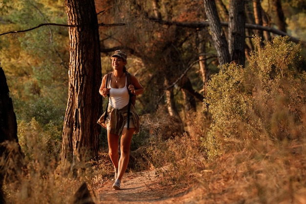 Viandante femminile felice che cammina attraverso la foresta