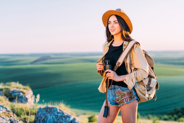 Viandante femminile sorridente che tiene binoculare