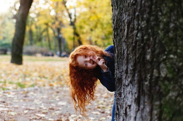 Vibrazioni autunnali, ritratto del bambino. La piccola ragazza affascinante e rossa sembra felice camminando e giocando su t