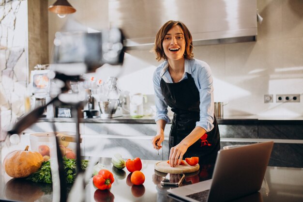 Videoblogger della giovane donna che cucina alla cucina e alle riprese