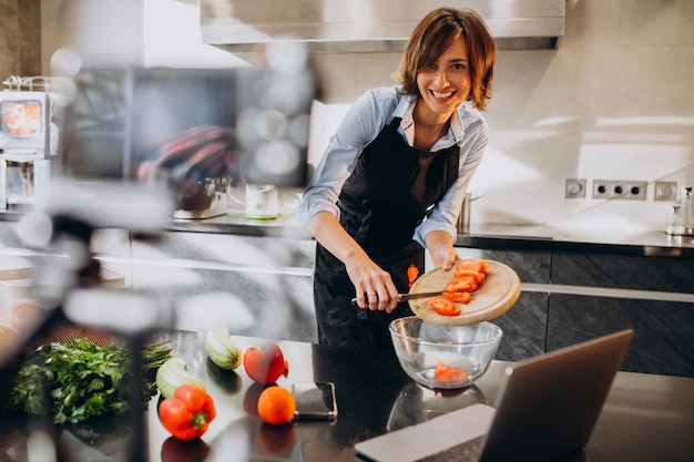 Videoblogger della giovane donna che cucina alla cucina e alle riprese