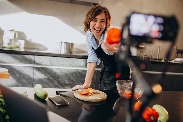 Videoblogger della giovane donna che cucina alla cucina e alle riprese