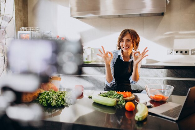 Videoblogger della giovane donna che cucina alla cucina e alle riprese