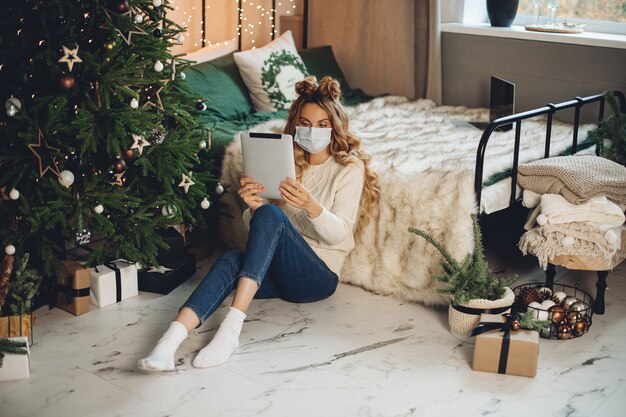 Videochiamata donna bionda tramite pad dalla camera da letto a Natale. Pandemia e concetto di blocco.