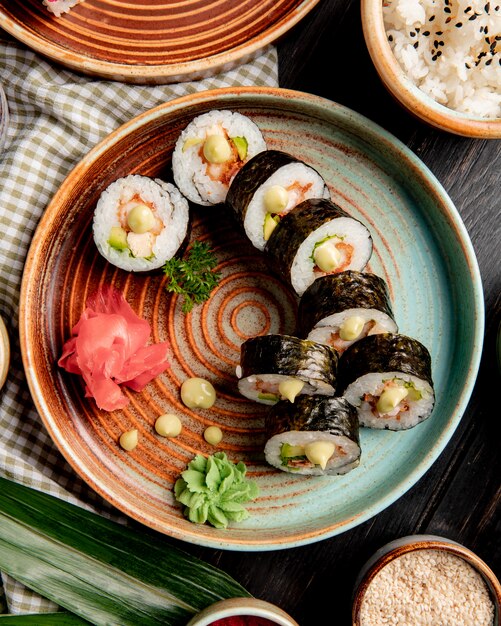 vie principali di involtini di sushi con gamberi tempura di avocado e crema di formaggio su un piatto con zenzero e wasabi