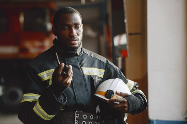 Vigile del fuoco arfican in uniforme. L'uomo si prepara a lavorare. Guy usa il trasmettitore radio.