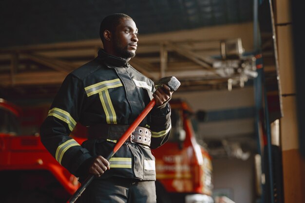 Vigile del fuoco arfican in uniforme. L'uomo si prepara a lavorare. Ragazzo con hummer.