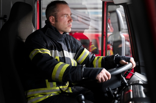 Vigile del fuoco maschio alla stazione all'interno del camion dei pompieri