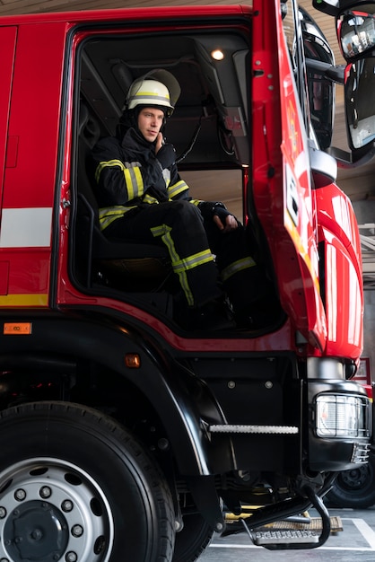 Vigile del fuoco maschio alla stazione dotato di tuta e casco di sicurezza