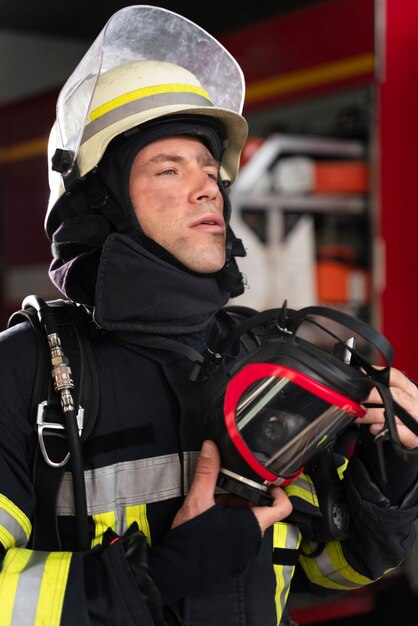 Vigile del fuoco maschio alla stazione in tuta e casco