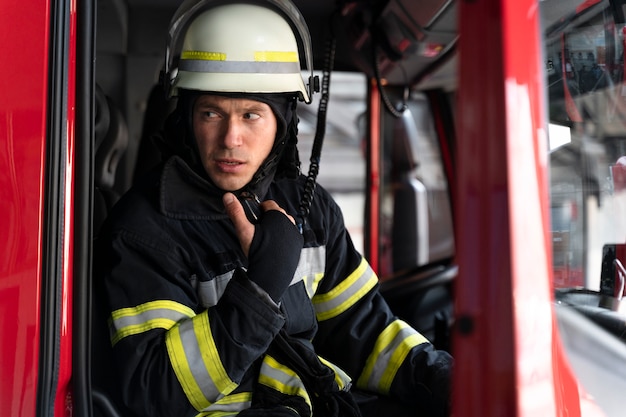 Vigile del fuoco maschio in camion dei pompieri utilizzando la stazione radio