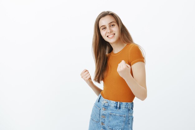 Vincente ragazza felice di successo che balla come una campionessa, sorridendo soddisfatta come trionfante