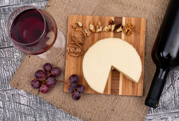 Vino di vista superiore con l'uva e il formaggio a bordo e sull'orizzontale di legno bianco