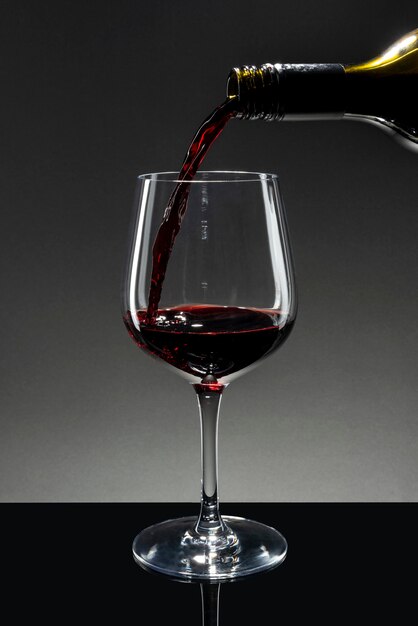 Vino rosso che si versa in un bicchiere da vino