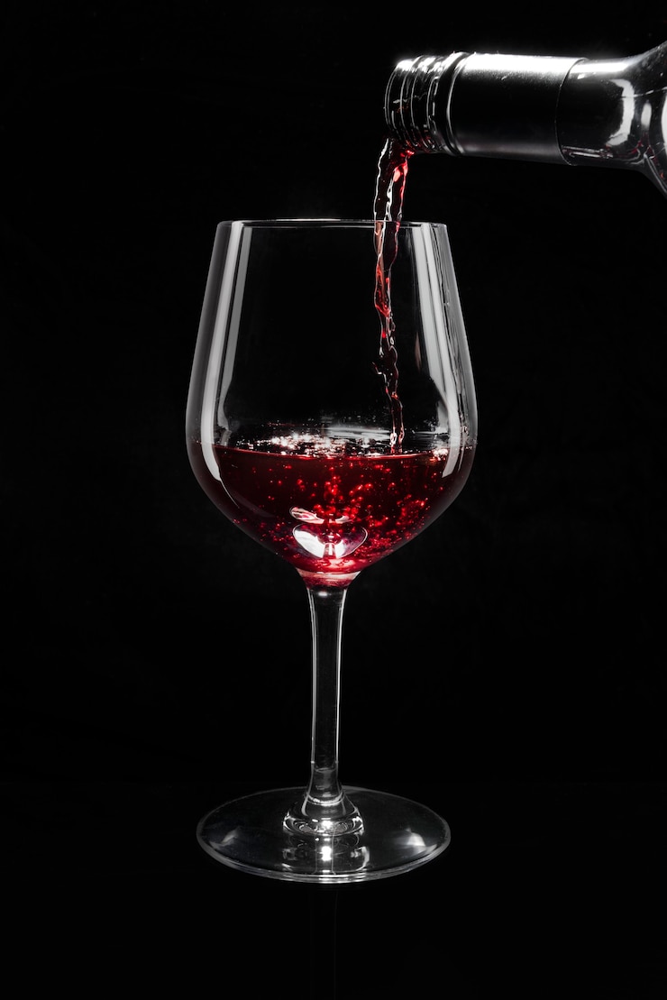 Foto gratuito vino rosso che versa in un bicchiere di vino