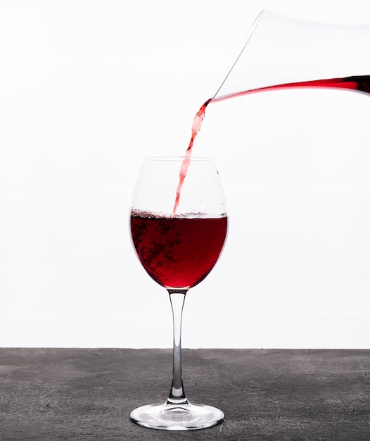 Vino rosso di vista laterale in vetro sul verticale bianco