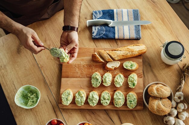 Vista ad alto angolo di un cuoco irriconoscibile che prepara bruschette di avocado in cucina