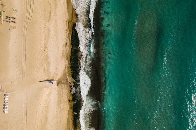 Vista aerea della sabbia che incontra l'acqua e le onde di mare