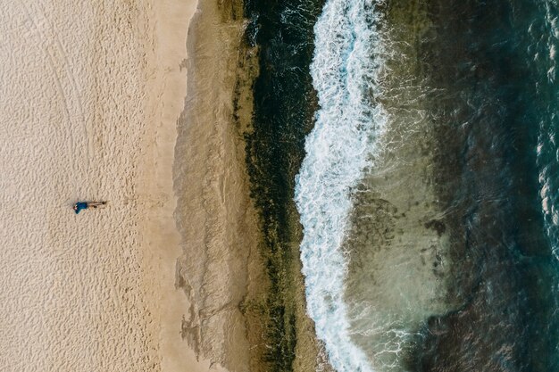 Vista aerea della sabbia che incontra l'acqua e le onde di mare