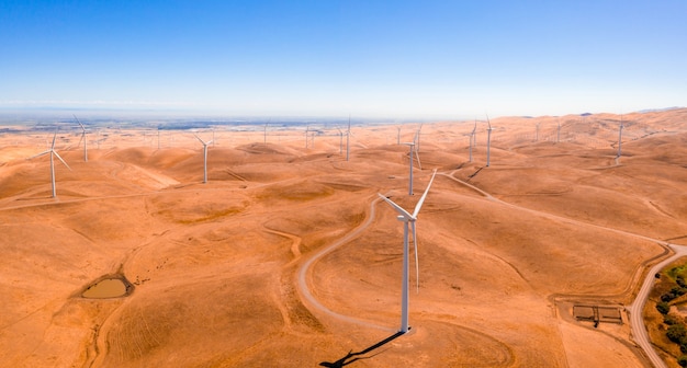 Vista aerea delle turbine eoliche e strada sinuosa sul bellissimo paesaggio montano dorato in California