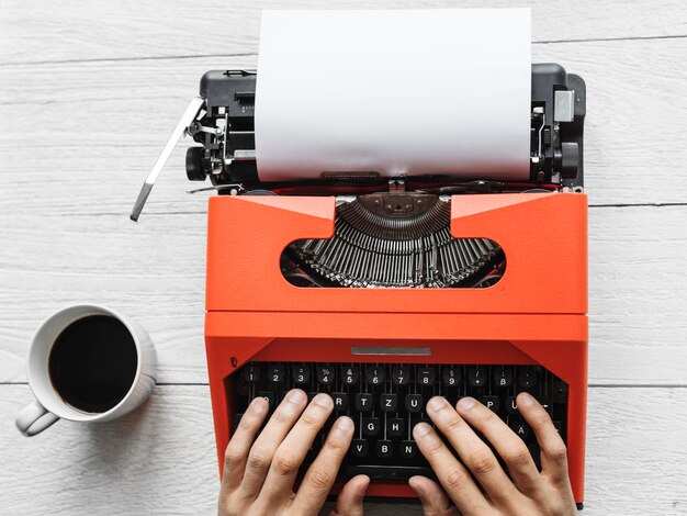 Vista aerea di un uomo che scrive su una carta bianca per macchina da scrivere retrò
