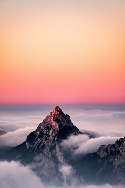 Vista aerea di una montagna coperta di nebbia sotto il bel cielo rosa