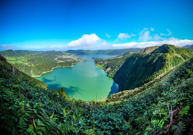 Vista affascinante del lago circondato da montagne ricoperte di verde sotto il cielo blu