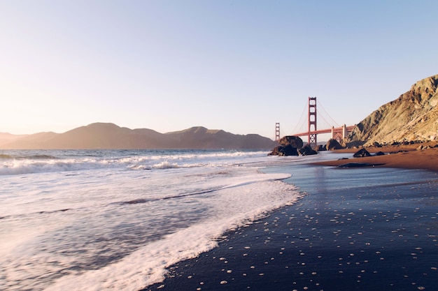 Vista affascinante dell'oceano calmo con il ponte e le montagne sullo sfondo, USA