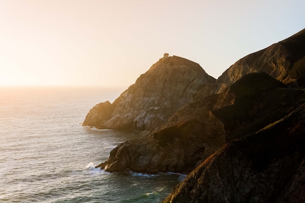 Vista affascinante dell'oceano calmo e delle scogliere sulla riva sotto il cielo blu durante il tramonto